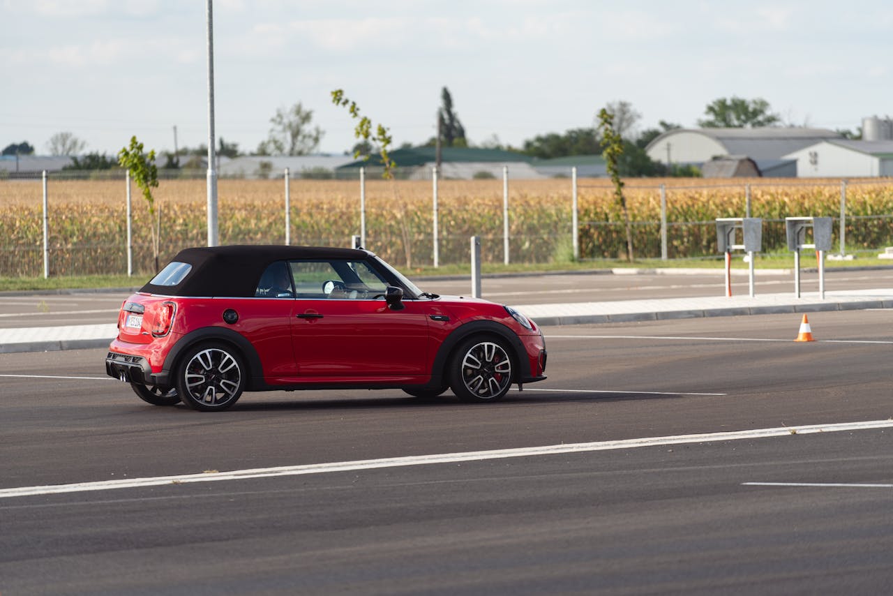 Side view of a red Mini Cooper convertible parked outdoors in Balatonfőkajár, Hungary.